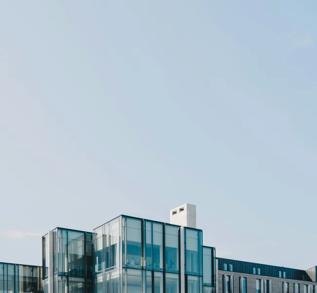 Moderne Gebäudefassade mit Glaselementen vor blauem Himmel